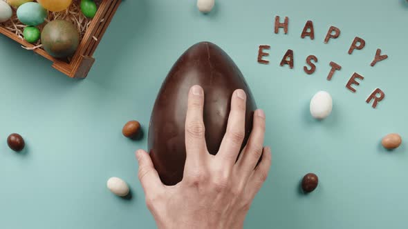 Hand Opens a Chocolate Easter Egg with a Gift Rabbit Inside