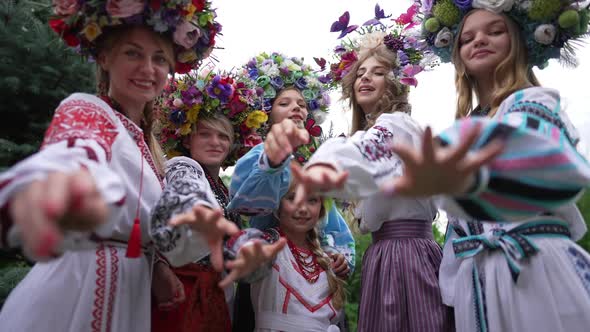 Little Ukrainian Girl and Group of Women Stretching Hands to Camera Standing in Green Summer Spring