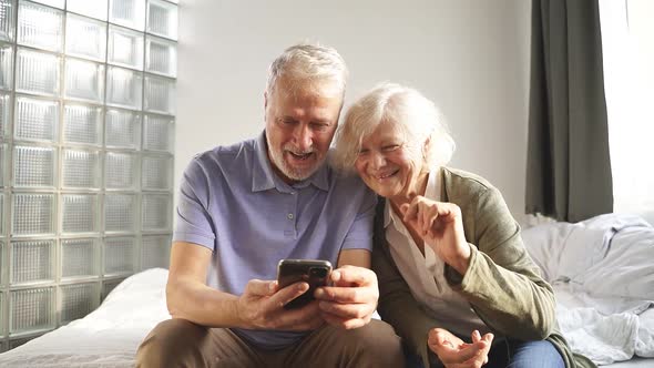 Happy Elderly Couple Using Their Smartphone Make a Video Call with Friends and Family