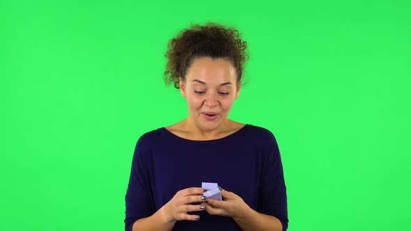 Portrait of Curly Woman Opening Small Box with a Surprise and Very Rejoicing . Green Screen