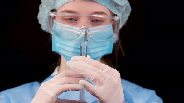 Professional Female Doctor Holds a Syringe with a Vaccine on a Black Background