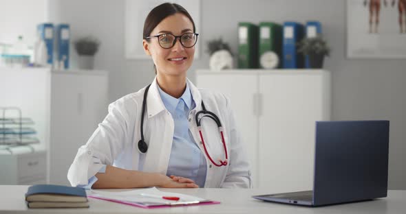 Portrait of Smiling Female Doctor Working on Laptop in Clinic Office