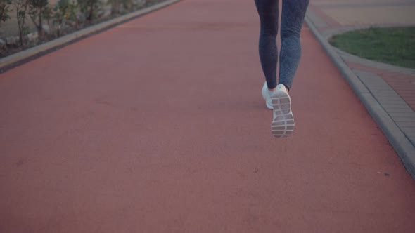 Close Up Shot of Sporty Woman with Slim Figure Running Outdoors in Twilight, Back View