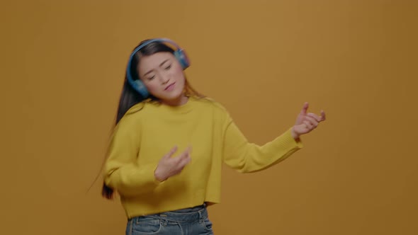 Asian Woman Playing Air Guitar and Wearing Headphones