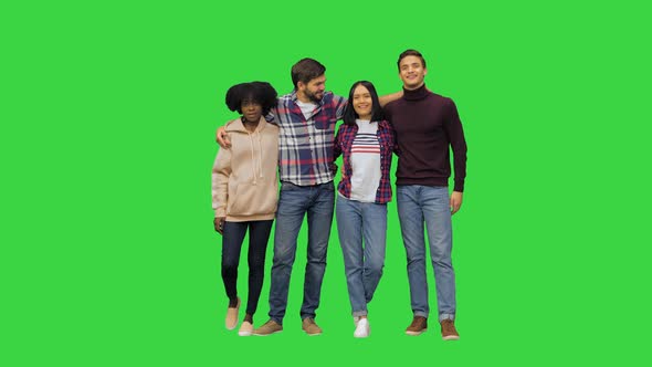 Four Happy Friends Posing for a Picture Hugging All Together and Smiling at the Camera on a Green