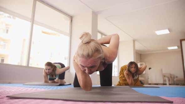 Three Women Do Yoga  Lie with Their Heads to the Floor and Stretch Their Leg to the Side