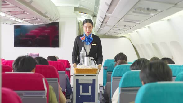 Asian air hostess walking on aisle checking and giving service to all passengers along the way.