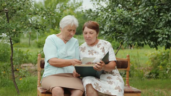 Two Elderly Women Look at Their Old Photos