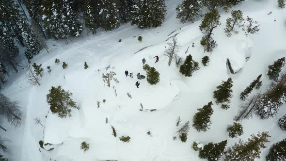 Aerial orbiting shot of a group of people on a snowy mountain