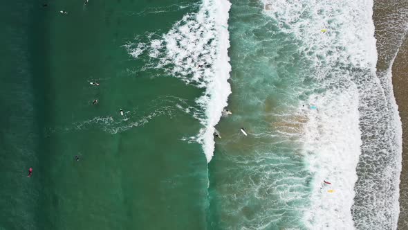 Surfers from above in Praia da Arrifana in west Portugal Atlantic coast, Aerial top view lowering ro