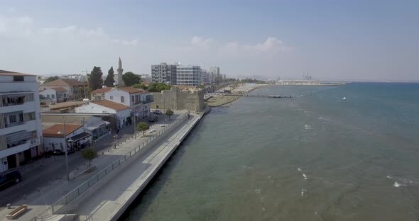 Drone aerial view of the boardwalk and cars driving along the coast as camera heads towards resorts