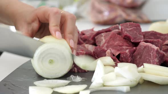 Woman Cutting Onion on Slices for Cooking Beef