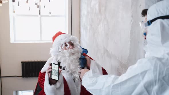 Santa Claus in Red Costume Shows QR Code Before Visiting the Christmas Party