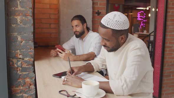 Black Man Writing in Cafe