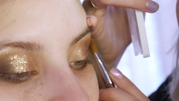 Professional Stylist Makeup Artist Makes Evening Eye Makeup to a Beautiful Girl Model