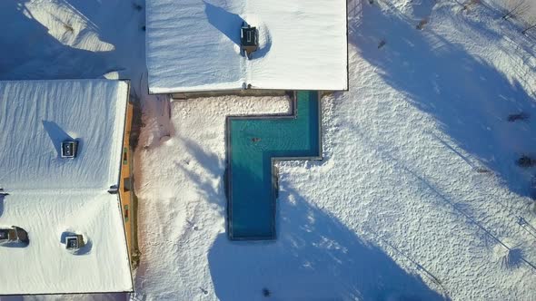 Aerial drone view of a woman swimming in a pool at a luxury spa resort.