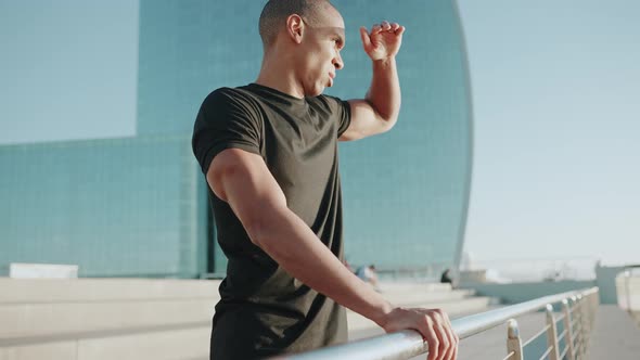 Handsome bald sportsman wearing black t-shirt looking around outdoors