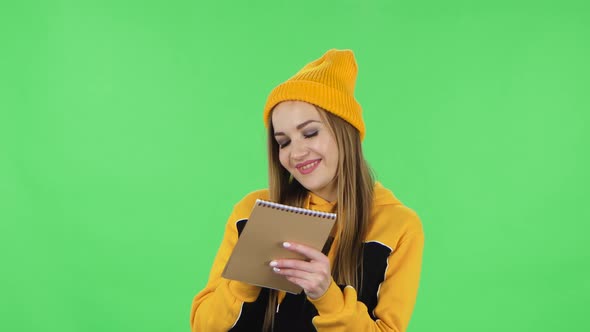 Portrait of Modern Girl in Yellow Hat Is Standing and Thinking, Then Happy Writing with Pencil