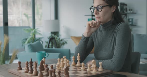 Smart woman playing chess at home