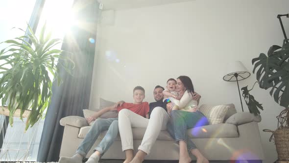 Happy Family Mom Dad and Cute Kids Relaxing on the Couch Laughing Having Fun Watching Tv