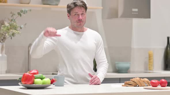 Man Showing Thumbs Down While Standing in Kitchen