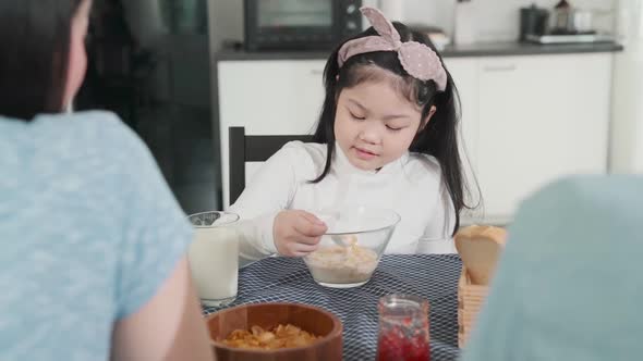 asian female child  boring food with mom and dad try to convince her to eat