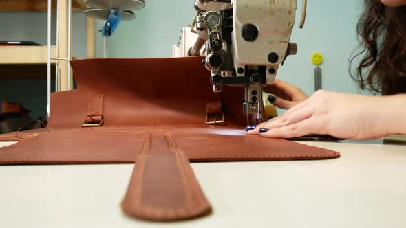 A Seamstress Sews a Pocket To a Leather Bag in a Sewing Workshop. A Woman Operates Sewing Machine