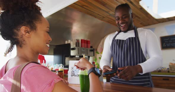 African american woman making payment from her smartwatch at the food truck