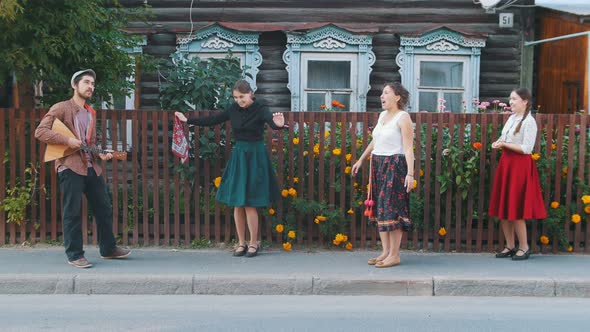 Young Women Dancing Folk Dances on the Street in the Village By the Music - a Man Playing Balalaika