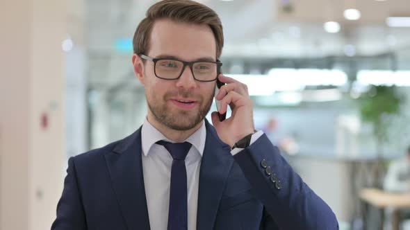 Businessman Talking on Smartphone, Discussing Work