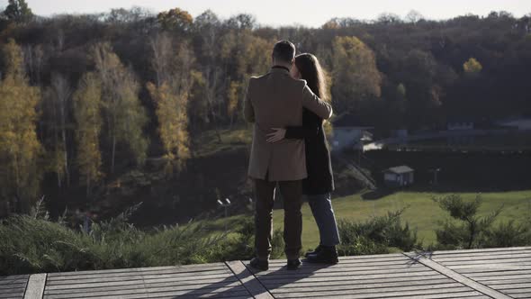 Wide Shot Back View of Happy Hugging Caucasian Couple Standing on Wooden Bridge in Countryside