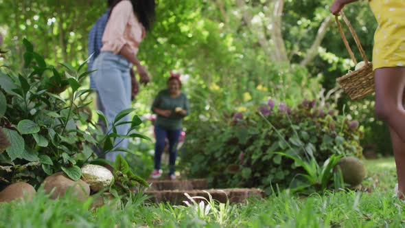 Animation of happy african american family searching for easter eggs in garden