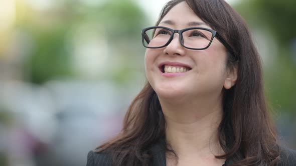 Mature Happy Beautiful Asian Businesswoman Thinking in the Streets Outdoors