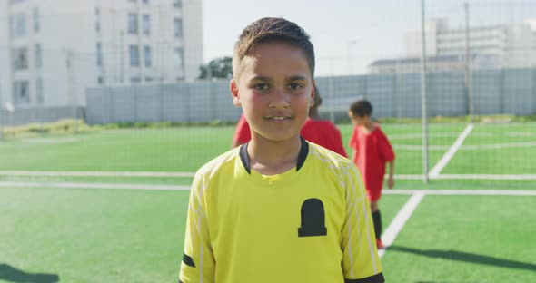 Mixed race soccer kid in red smiling and looking at camera