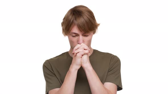 Portrait of Concentrated Blond Male Keeping Hands Together for Praying Pleading Hard Over White