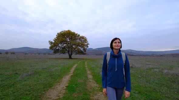 Woman Walking a Dirt Road with an Oak Tree