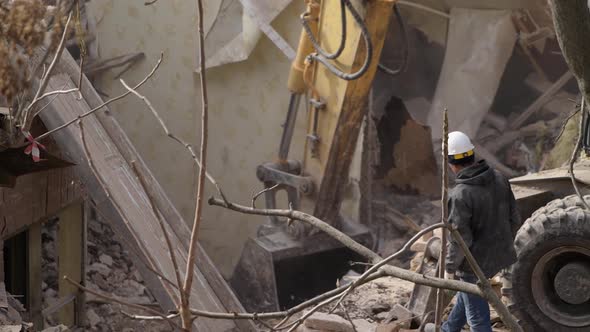 Engineer with Protective Helmet Looks at Demolition Destruction of Old Building Excavator Breaks