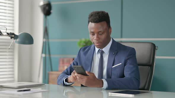 Attractive African Businessman Using Smartphone in Office