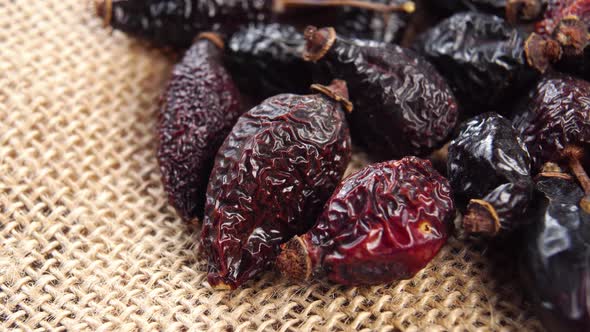 Dried wrinkled briar berries. Dry rose hips. Dog-rose fruits on a rough rustic burlap. Macro