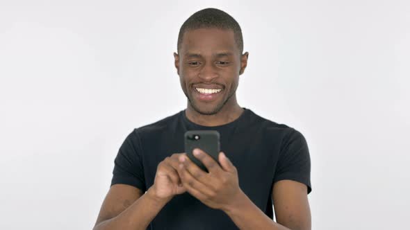 Young African Man Browsing Smartphone on White Background