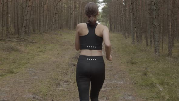 An Athlete Running Along a Forest Trail