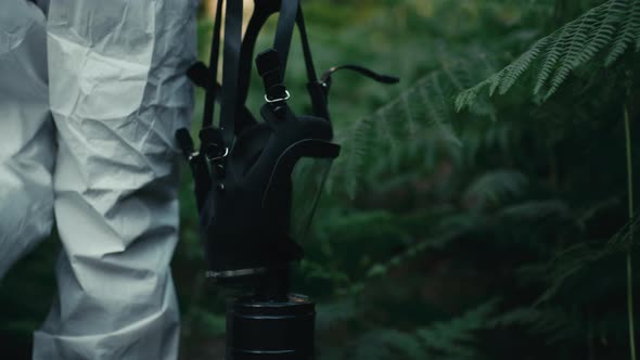 Man Walks with Gas Mask in Hand in the Forest