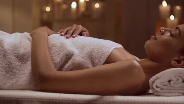 Tranquil African American Beautiful Female Lying in Day Spa Preparing for Massage