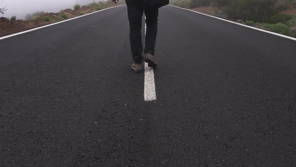 Man Walking Down Middle Of Empty And Misty Road