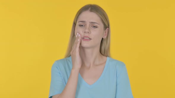 Young Woman having Toothache on Yellow Background