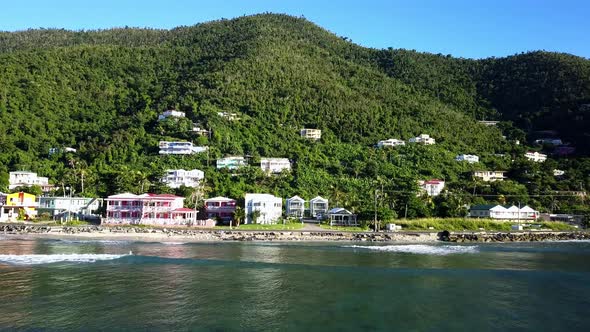 Aerial fly into local homes over a beach on BVI island Tortola