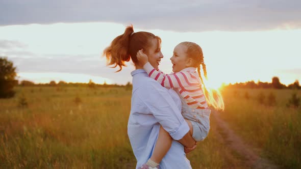 Mother Holding Cute Daughter in Arms Hugging Each Other Spinning and Laughing