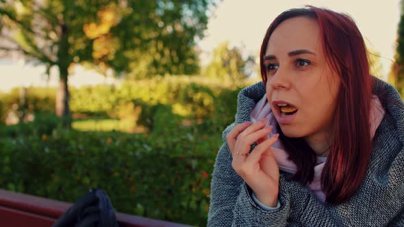 Portrait of a Beautiful Woman Who is Sitting in the Park on a Sunny Autumn Day Eating Potato Chips