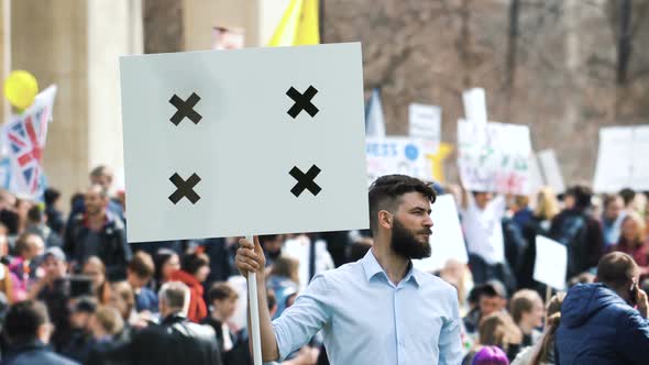 Serious Man Banner in background of Crowd. European People with Placard on Demonstration. American.