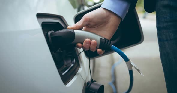 Mid section of caucasian man charging electric car